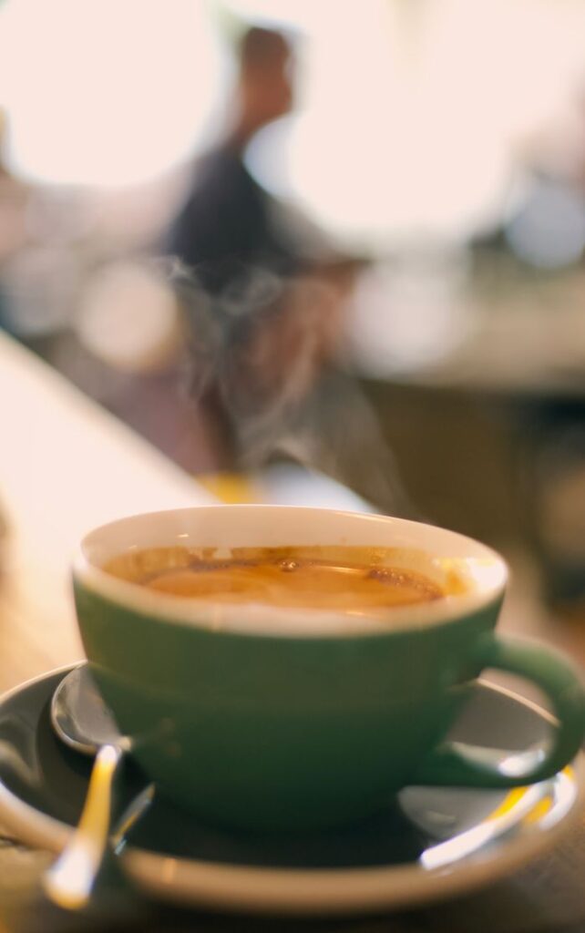 A steaming coffee cup on a table with a blurred cafe background, capturing a warm ambiance.